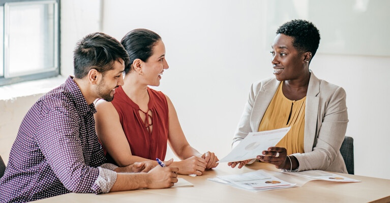 A real estate agent showing paperwork to a man and a woman.