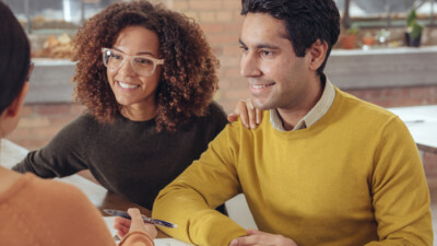 Woman and man smiling and signing documents.