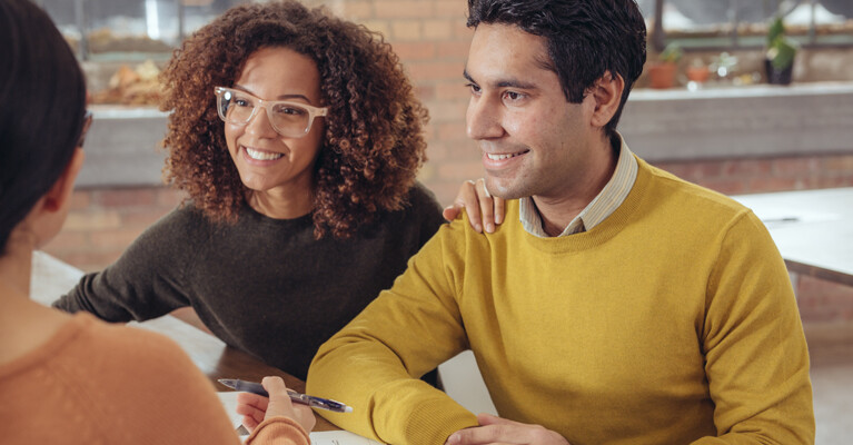 Woman and man smiling and signing documents.