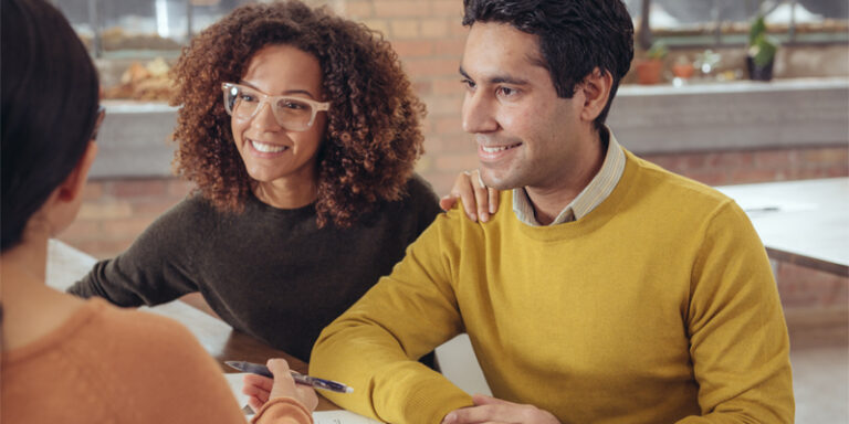 Woman and man smiling and signing documents.