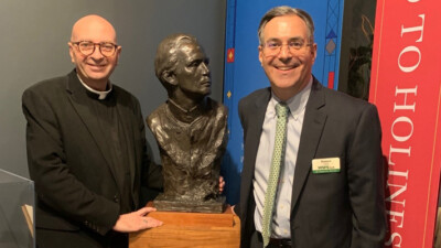 A WSFS Associate posing beside a bust of Saint John Neumann.