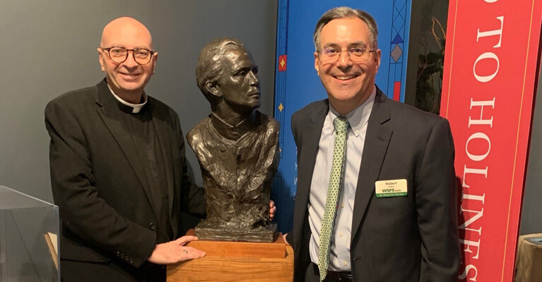 A WSFS Associate posing beside a bust of Saint John Neumann.