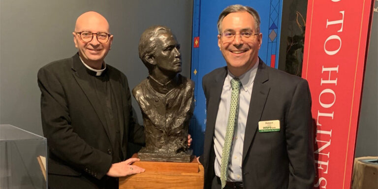 A WSFS Associate posing beside a bust of Saint John Neumann.