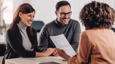 A banker going over paperwork with a man and a woman.