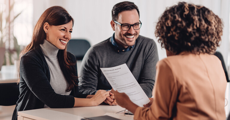 A banker going over paperwork with a man and a woman.