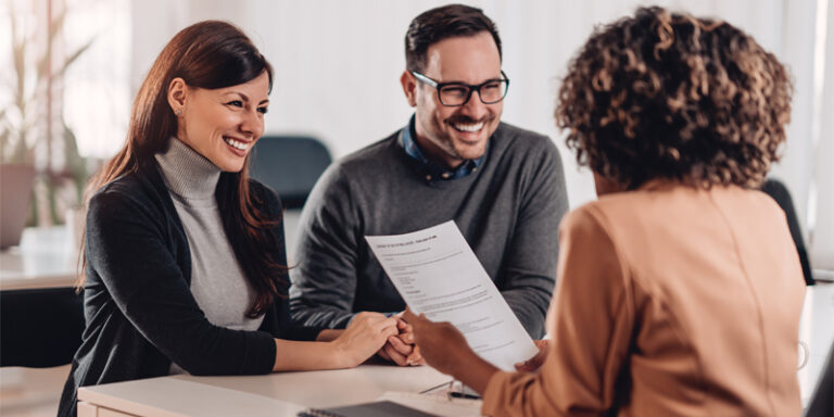 A banker going over paperwork with a man and a woman.