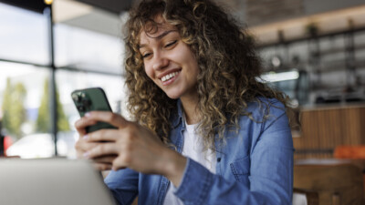 Woman smiling and looking at a cell phone.