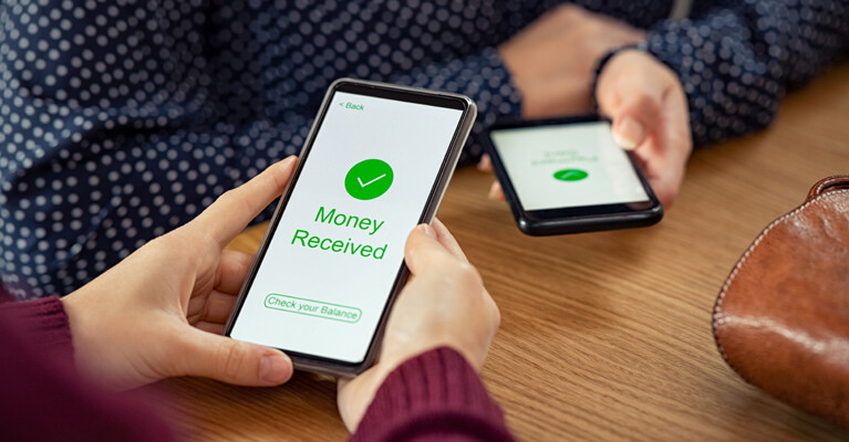 Two cell phones displaying an electronic money transfer, one screen reading "Money received. Check your balance."