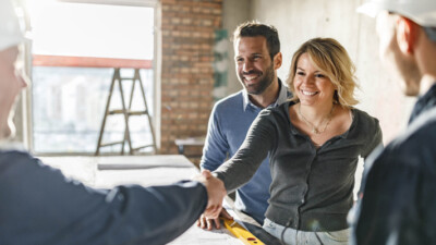 Man and woman shaking hands with construction workers.