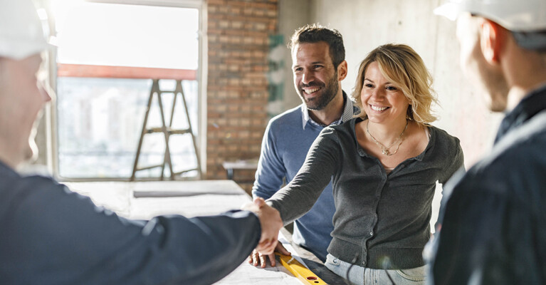 Man and woman shaking hands with construction workers.