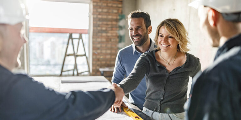 Man and woman shaking hands with construction workers.