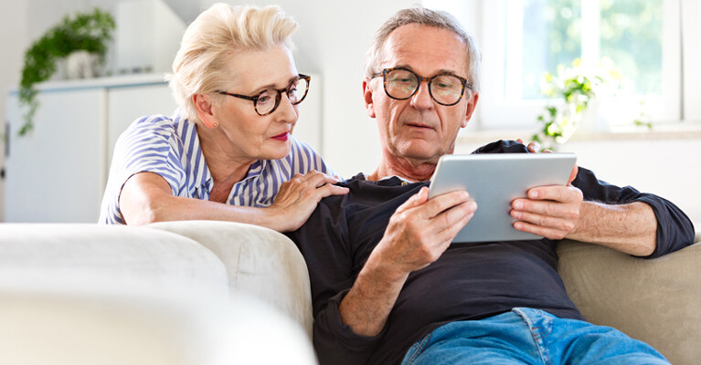 A man and a woman looking at a tablet.