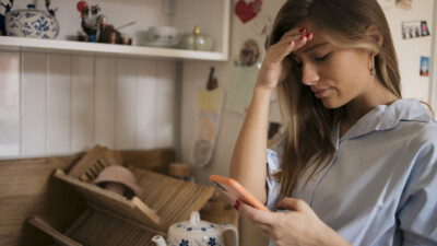 A woman looking concerned by the scam text message on her phone.