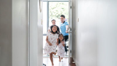 Two children running through a doorway, their parents in the background.