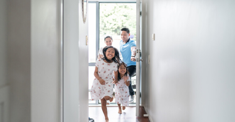 Two children running through a doorway, their parents in the background.