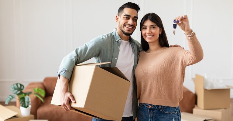 New home owners holding house keys and a moving box.