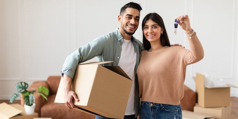 New home owners holding house keys and a moving box.
