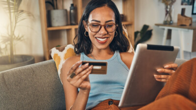 A woman holding a credit card and a tablet.