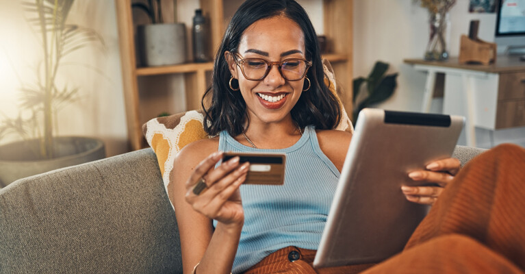 A woman holding a credit card and a tablet.