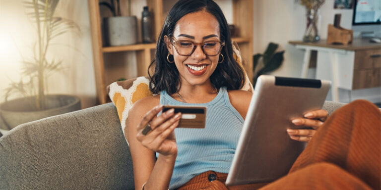 A woman holding a credit card and a tablet.
