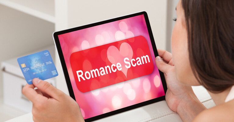 A person looking at their credit card and a tablet that says, “romance scam.”