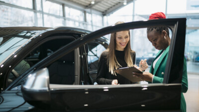 A customer and a car salesman signing paperwork for a new car.