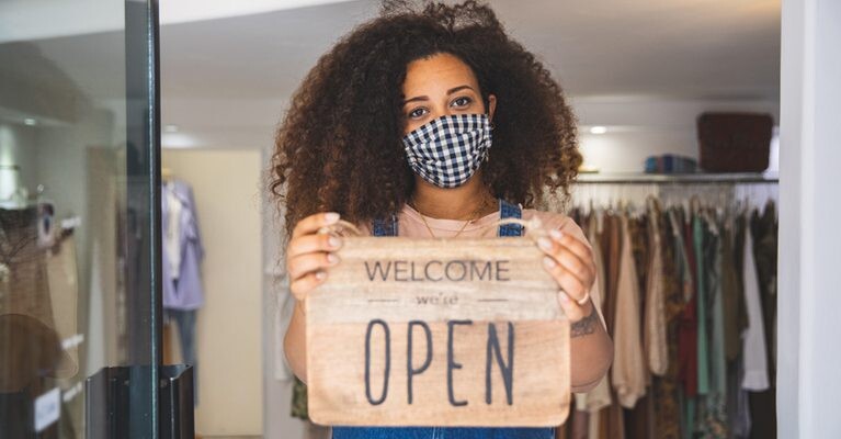Small business owner holding an "Open" sign.