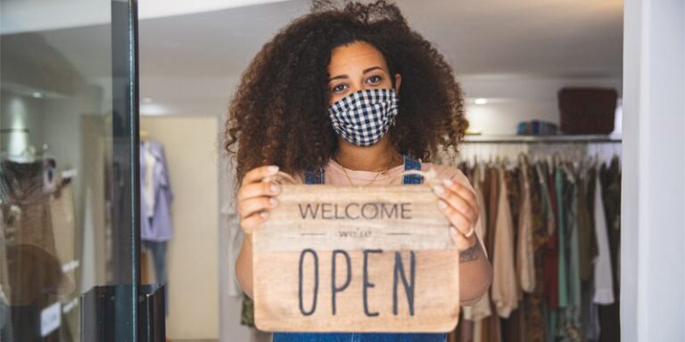 Small business owner holding an "Open" sign.