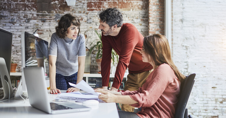 A group of employees from a small business discussing ways to drive revenue.