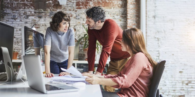 A group of employees from a small business discussing ways to drive revenue.