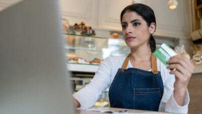 A cafe manager making an online purchase with a credit card.