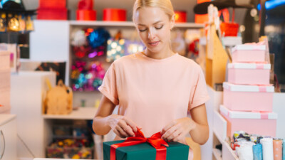 A woman tying a bow on a gift box.