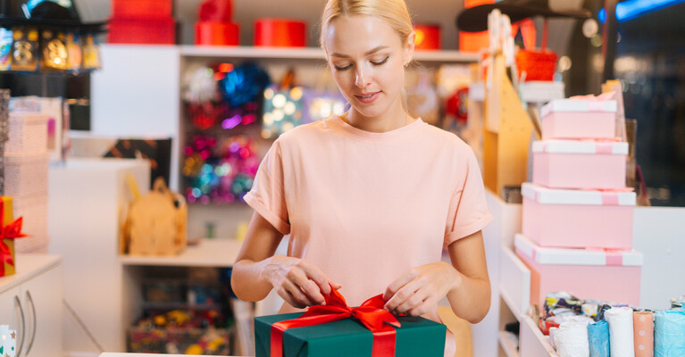 A woman tying a bow on a gift box.