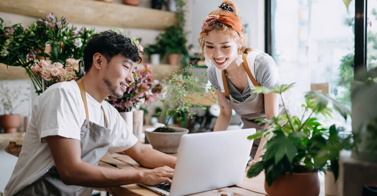 Small business owners smiling at laptop.