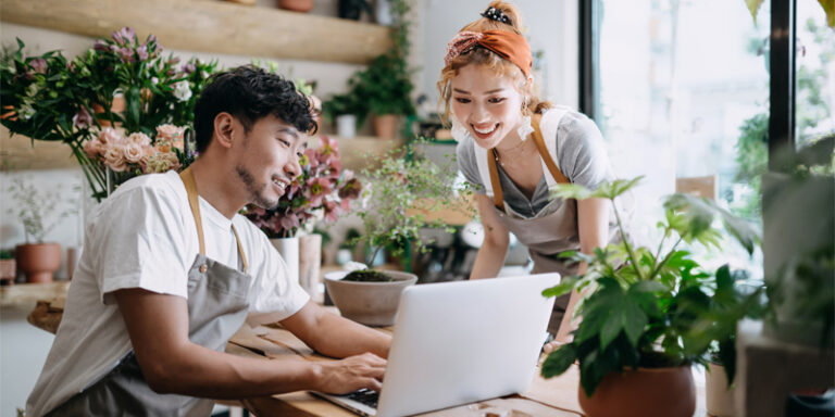 Small business owners smiling at laptop.