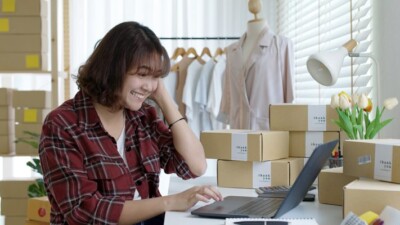 Small business owner packaging orders in front of computer.