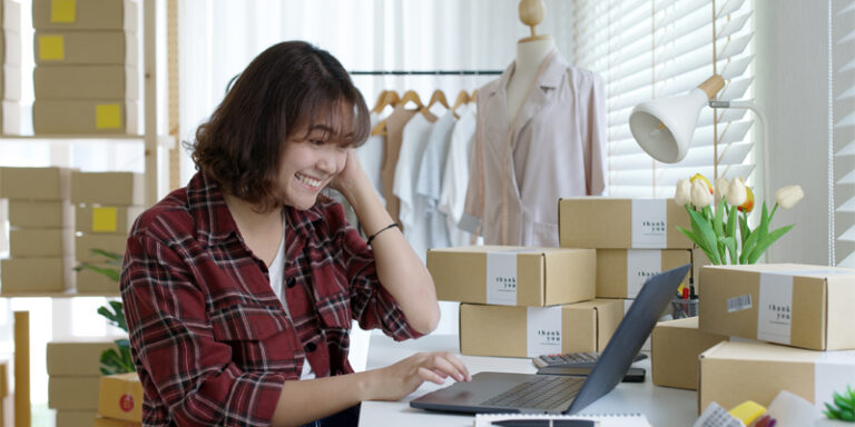 Small business owner packaging orders in front of computer.