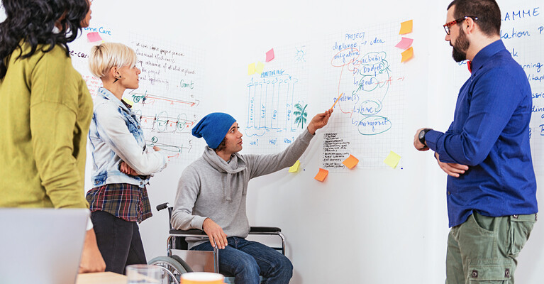Workers using a whiteboard to brainstorm.