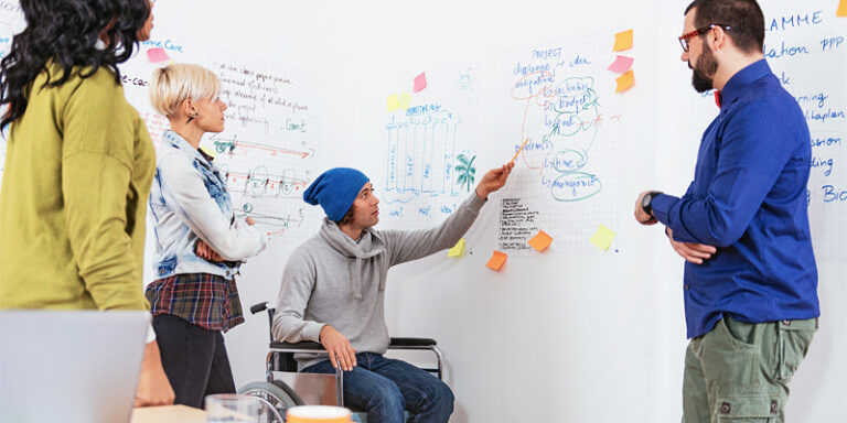 Workers using a whiteboard to brainstorm.