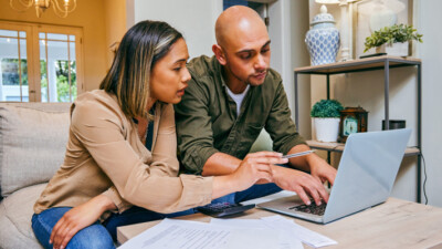 A man and woman calculating their finances on a laptop.