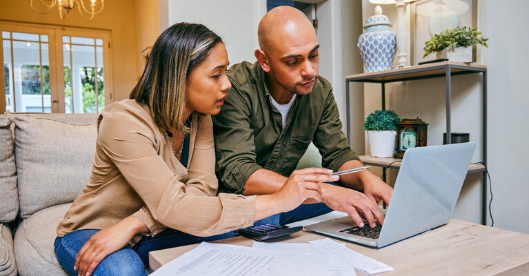 A man and woman calculating their finances on a laptop.