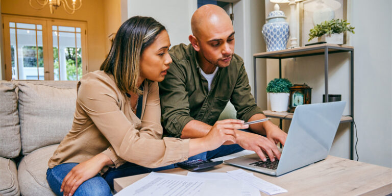 A man and woman calculating their finances on a laptop.