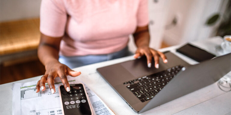 A woman using a laptop and her phone.