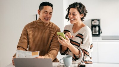 Man and woman conversing and looking at cell phone.