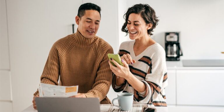Man and woman conversing and looking at cell phone.