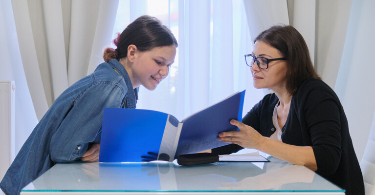 Teenage girl and woman looking at a folder.