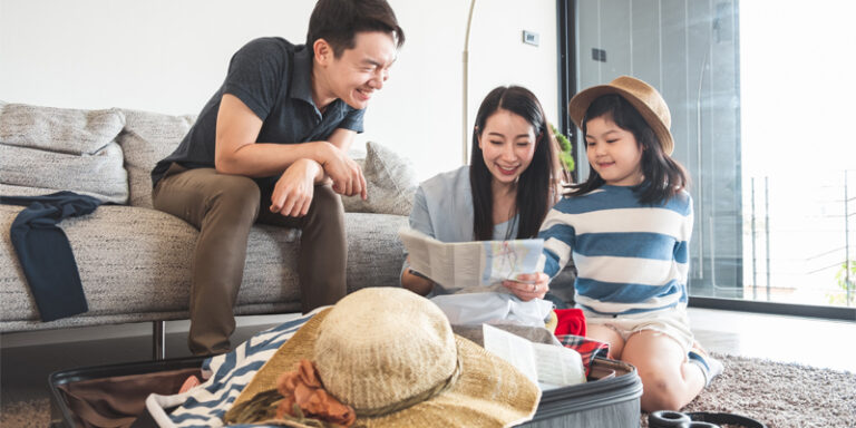 Man, woman, and child looking at map and packing suitcase.