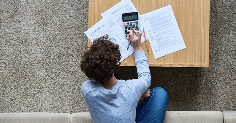 A man filling out forms and using a calculator.