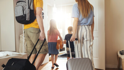 Man, woman, and two children, carrying suitcases.