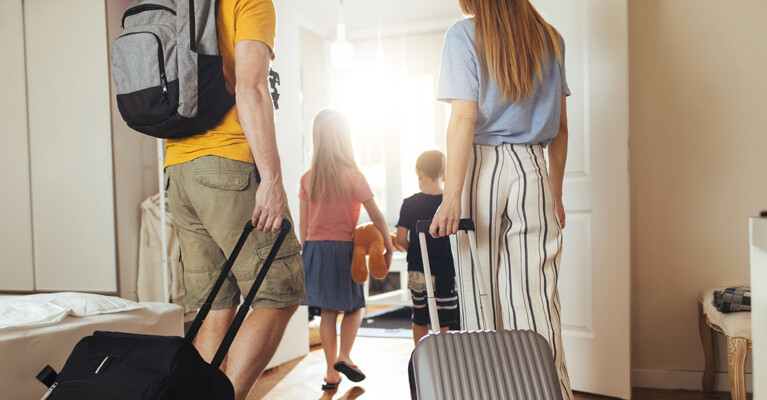Man, woman, and two children, carrying suitcases.